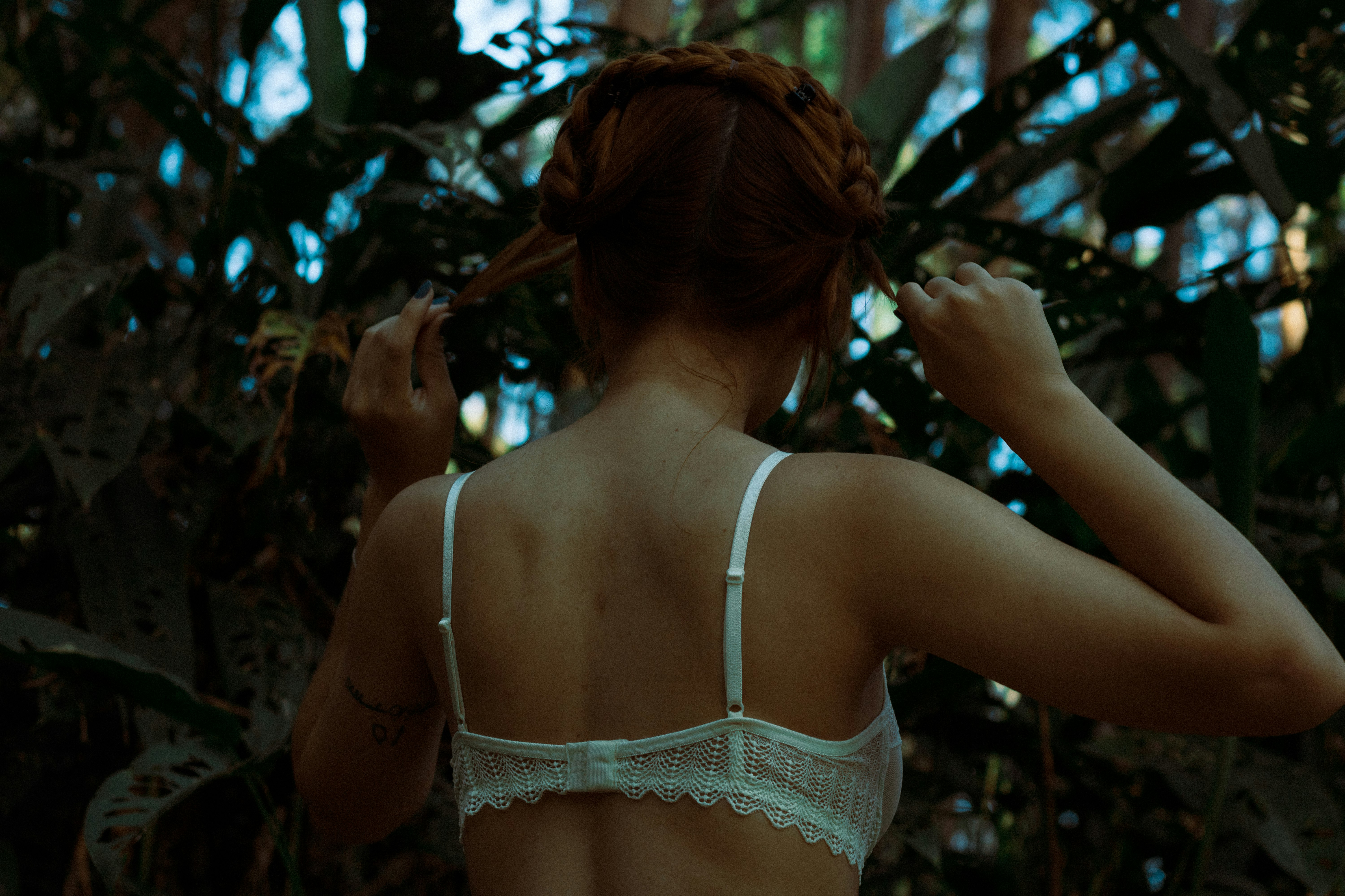 woman in white lace brassiere standing near green leaf tree during daytime